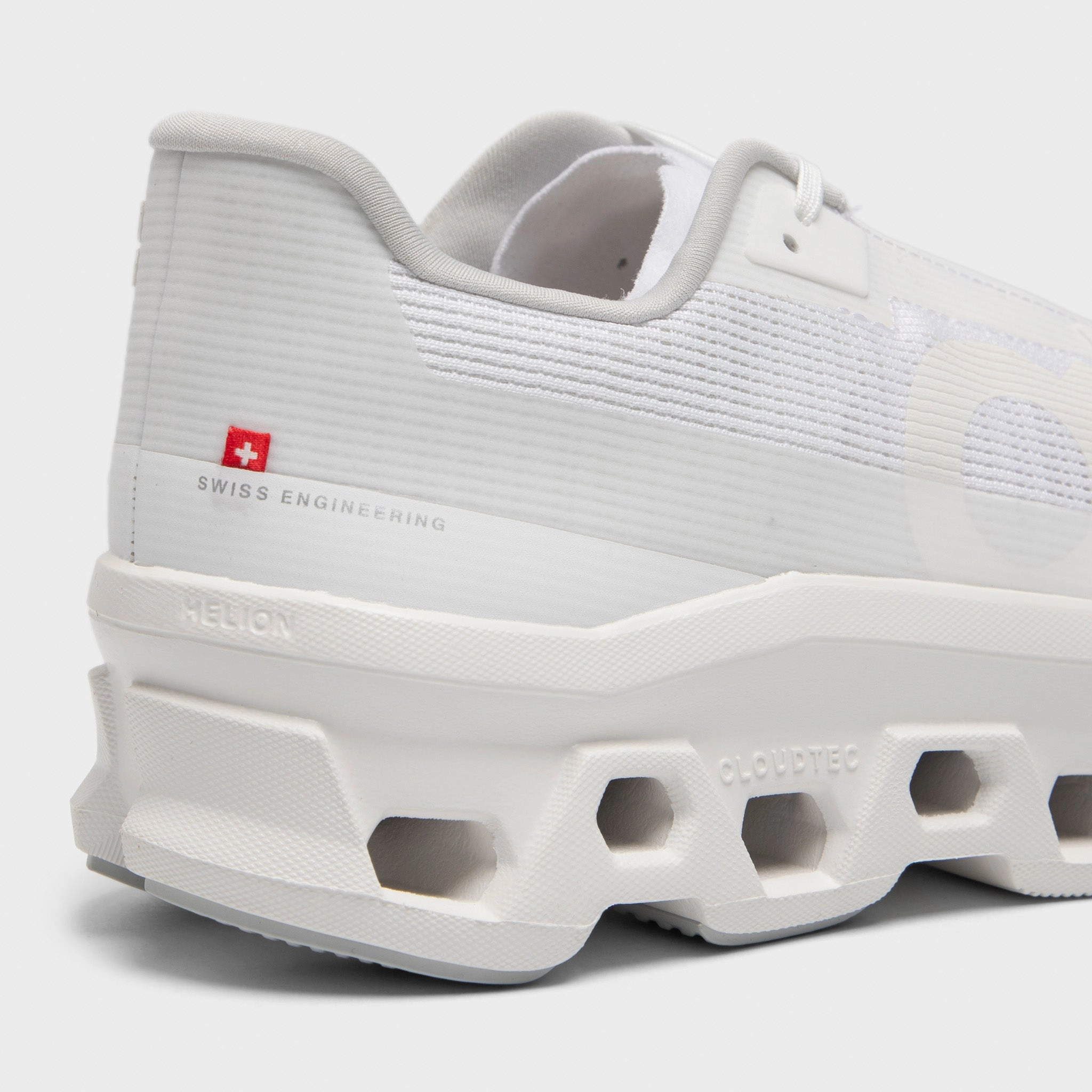 On Cloudmonster Void White / White running in a baseball field area shoes